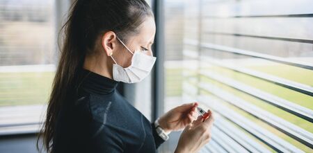 Worried woman with thermometer and face masks indoors at home, Corona virus concept.