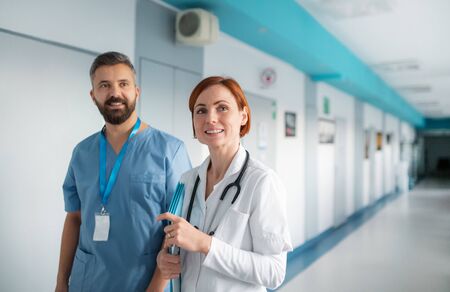 Portrait of man and woman doctor walking in hospital, looking at camera.の写真素材