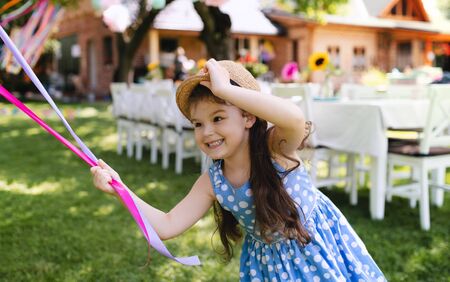 Small girl outdoors in garden in summer, playing with balloons.