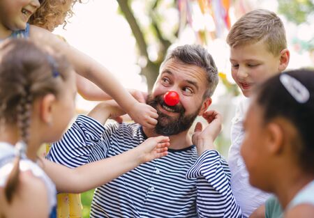Man with small children on ground outdoors in garden in summer, playing.の写真素材
