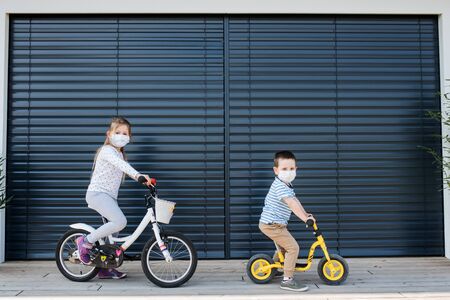 Small girl and boy with bicycles outdoors at home. Corona virus and quarantine concept.の写真素材