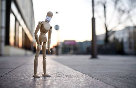 Wooden mannequin with face mask in town, corona virus and lockdown concept.の写真素材
