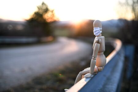 Wooden mannequin with face mask by road, corona virus and lockdown concept.の写真素材