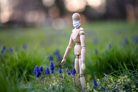 Wooden mannequin with face mask in nature, corona virus and lockdown concept.の写真素材