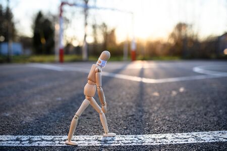 Wooden mannequin with face mask in town, corona virus and lockdown concept.の写真素材