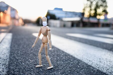 Wooden mannequin with face mask in town, corona virus and lockdown concept.の写真素材