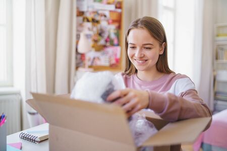 Young female student at the table, opening parcel box.