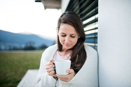 Woman with coffee outdoors at home, Corona virus and quarantine concept.の写真素材