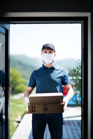 Courier with face mask delivering parcel, corona virus and quarantine concept.の写真素材
