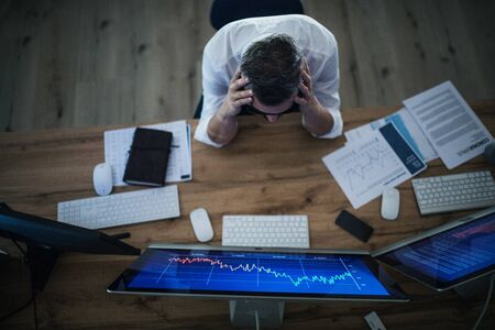 Top view of frustrated businessman with computer working at desk. Financial crisis concept.