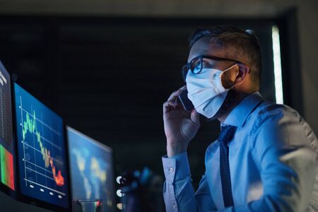 Businessman with computer sitting at desk, working late. Financial crisis concept.の写真素材