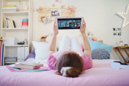 Young girl with tablet on bed, relaxing during quarantine. Copy space.の写真素材