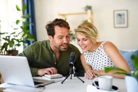 Happy couple with microphone having video call on laptop indoors at home.