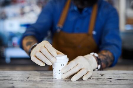 Barista working with gloves, coffee shop open after lockdown quarantine.