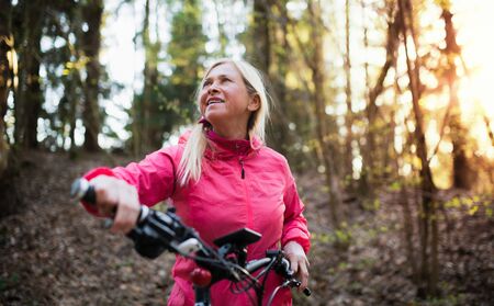 Active senior woman with e-bike cycling outdoors in nature.の写真素材