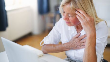 Frustrated woman engineer with laptop indoors in home office, feeling pain.の写真素材