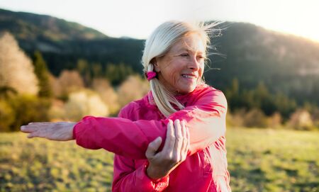 Attractive senior woman doing exercise outdoors in nature, stretching.の写真素材