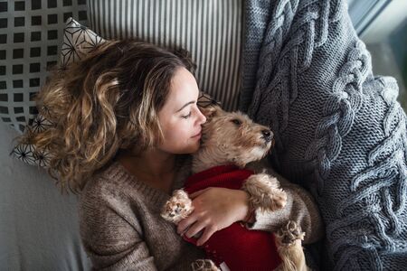 Top view of young woman relaxing indoors on sofa at home with pet dog.の写真素材
