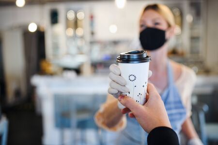 Woman with face mask serving customer, shop open after lockdown quarantine.の写真素材