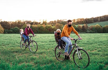 Family with two small children on cycling trip, wearing face masks.