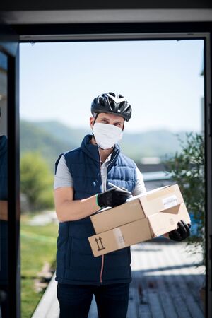 Courier with face mask delivering parcel, corona virus and quarantine concept.の写真素材