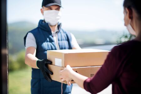 Courier with face mask delivering parcel, corona virus and quarantine concept.の写真素材