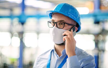 Technician or engineer with protective mask and telephone working in industrial factory.の写真素材