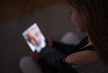 Unrecognizable young girl with laptop at night smiling, online dating concept.の写真素材