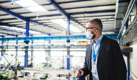 Technician or engineer with protective mask standing in industrial factory.