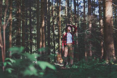 Young woman with a dog on a walk outdoors in forest in summer nature.の写真素材