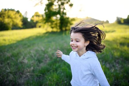 Portrait of small girl running outdoors in spring nature, laughing.の写真素材