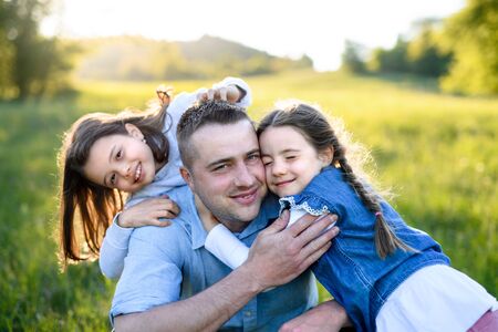 Father with two small daughters having fun outdoors in spring nature, hugging.の写真素材