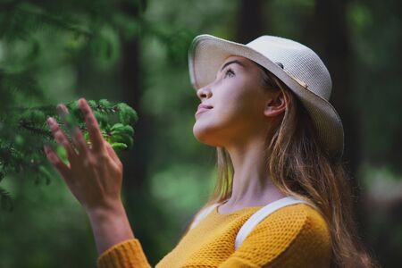 Young woman on a walk outdoors in forest in summer nature, daydreaming.