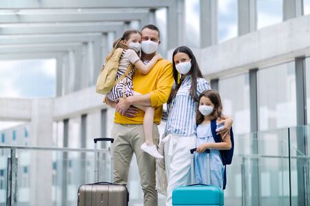 Family with two children going on holiday, wearing face masks at the airport.の写真素材