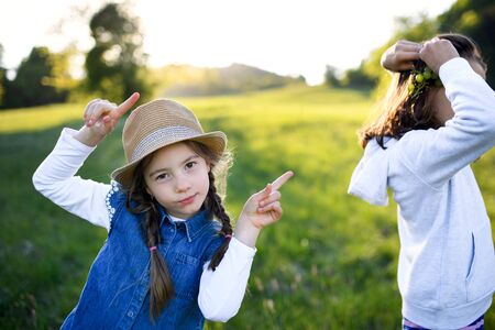 Portrait of two small girls standing outdoors in spring nature, having fun.の写真素材