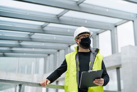 Portrait of worker with face mask at the airport, holding clipboard.