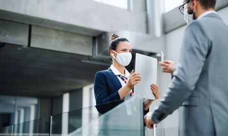 Flight attendant talking to businessman on airport, wearing face masks.の写真素材