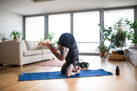 Young man doing workout exercise indoors at home, headstand.