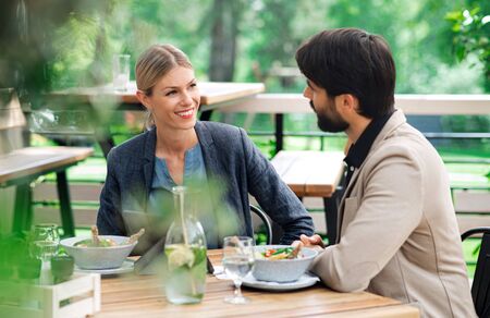 Happy couple sitting outdoors on terrace restaurant, talking.の写真素材