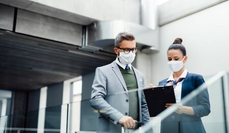 Flight attendant talking to businessman on airport, wearing face masks.の写真素材