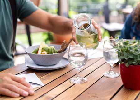 Midsection of couple sitting outdoors on terrace restaurant, having lunch.の写真素材