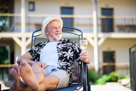 Senior man holding wine outdoors on holiday, relaxing.の写真素材