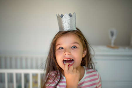 Portrait of small girl with princess crown on head indoors, looking at camera.の写真素材