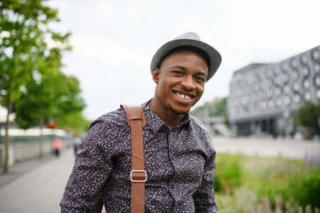 Cheerful young black man commuter outdoors in city, walking.の写真素材