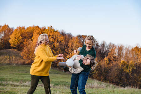 Small girl with mother and grandmother on a walk in autumn nature.