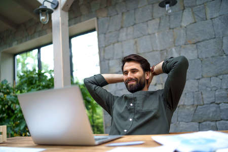 Young man with laptop sitting indoors in office, working.の写真素材