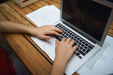 Unrecognizable woman with laptop sitting indoors in office, working.の写真素材