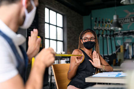 Young businesspeople with face masks working indoors in office, keeping safe distance.の写真素材
