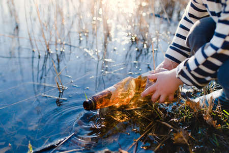 Unrecognizable small child collecting rubbish outdoors in nature, plogging concept.の写真素材