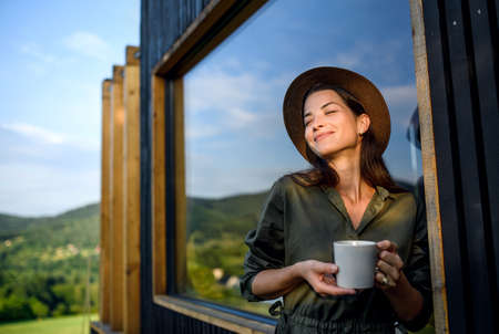 Young woman outdoors, weekend away in container house in countryside.